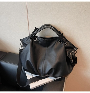 Détail du sac cabas en cuir grainé noir avec œillets métalliques et large bandoulière nylon