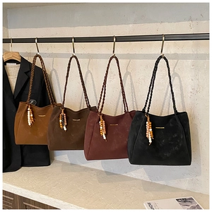 Macro detail of suede tote bags with woven straps and ethnic beaded charms in four colors
