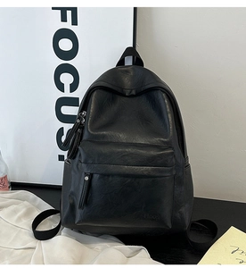 Close-up of black PU leather backpack featuring tassel zipper and embossed logo detail
