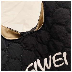 Close-up of black quilted nylon tote bag featuring white embroidered EIWEI letters