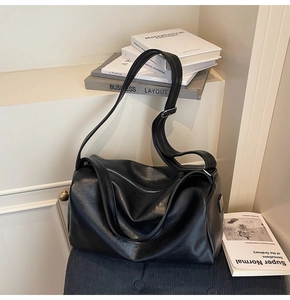 Detail of black faux leather tote featuring smooth texture and silver metallic zipper