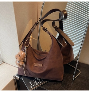 Detail of hobo bag in dark coffee suede with BANATO logo and cute plush bear charm