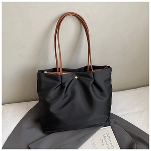 Detail of black nylon tote bag with brown straps and metal magnetic buckle for commuting