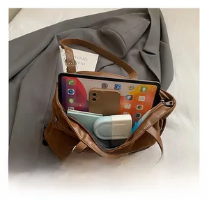 Detail view of large brown faux suede tote bag showing spacious interior with tablet and phone