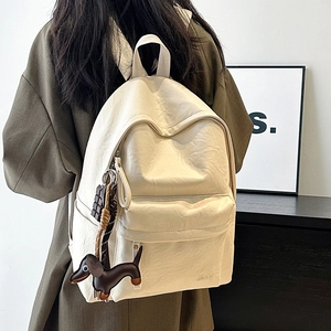 Detail of vintage cream PU backpack with chocolate charm and dachshund doll accessory