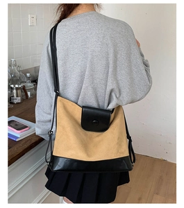 Detail view of large khaki crossbody bag with black leather trim worn by a model