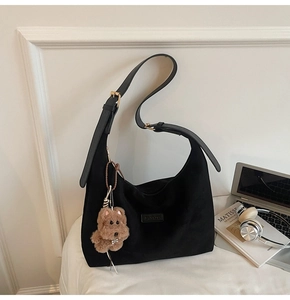 Detail of black suede tote bag with BANATO leather patch and brown plush dog charm