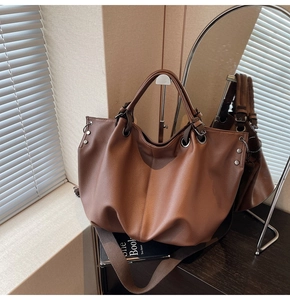 Détail du sac cabas marron en cuir à motif litchi avec œillets métalliques et ombres