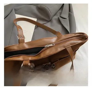 Detail of brown faux leather and suede patchwork bag with silver metal hardware