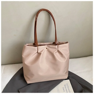 Close-up of minimalist tote bag in pale pink nylon fabric with brown leather handles