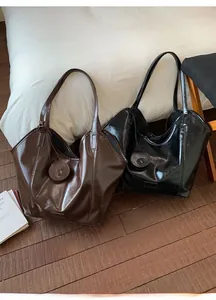 Detail view of glossy brown and black tote bags with minimalist straps and round charms