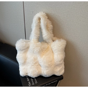 Gros plan sur la texture en fausse fourrure blanche et la large poignée du sac cabas