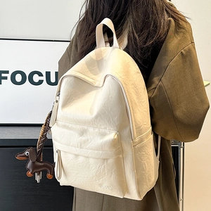 Close-up of beige leather backpack with Hoog logo and dachshund charm on model
