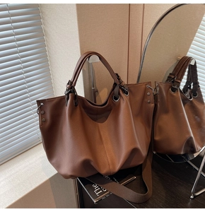 Détail de la poche fourre-tout en cuir grainé marron foncé avec rivet et anneau doré