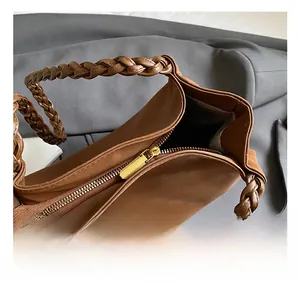 Macro view of a brown tote bag featuring woven handles and gold metal zipper details