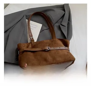 Detail of brown vintage suede tote bag with decorative metal buckle and smooth leather base