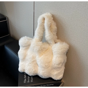 Détail d'un sac cabas en fausse fourrure beige posé sur des livres avec texture douce