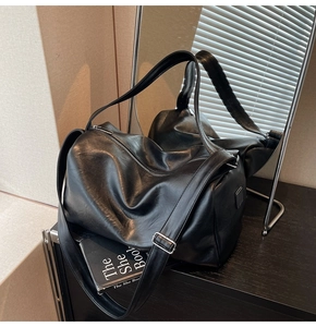 Detailed shot of black faux leather tote featuring square metal logo and silver zipper
