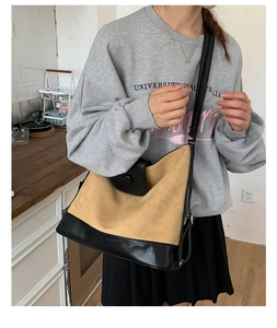 Close-up of khaki suede and black leather patchwork crossbody bag worn by a model