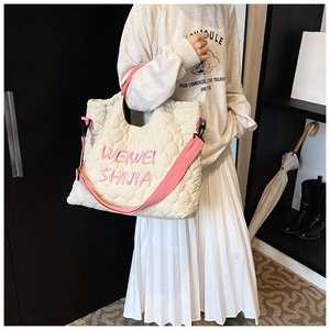 Quilted cream tote bag with pink straps and adjustable shoulder belt worn by a model