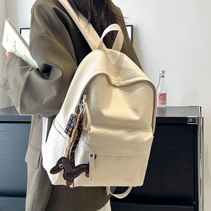 Side view of beige nylon backpack with cute chocolate and dachshund charms detail