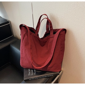 Close-up of red checkered canvas tote bag with dual straps and textured fabric detail