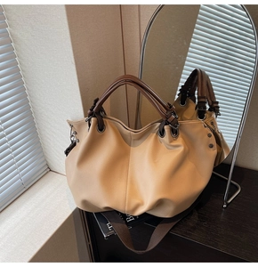 Détail du sac cabas beige avec motif litchi, poignées marron et rivets métalliques