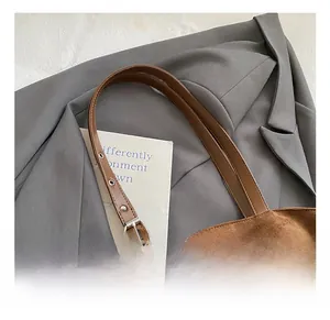 Detailed close-up of brown suede tote bag with adjustable leather strap and metal buckle