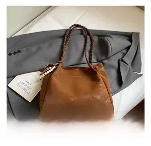 Detail of brown suede tote bag with woven handles and beaded tassel charm accent
