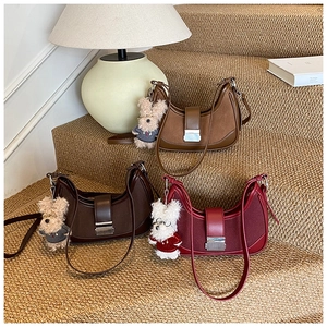 Detailed view of hobo shoulder bags in suede with plush dog charms on indoor stairs