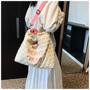 Detail of cream quilted tote bag with pink embroidery and adjustable drawstrings