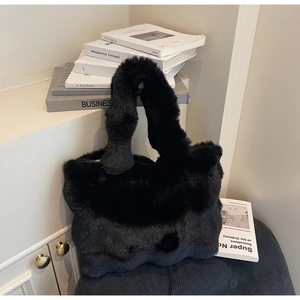 Détail du sac cabas noir en fausse fourrure montrant la texture douce et la poignée