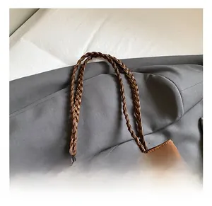 Detail of dark brown leather tote featuring woven handles and bohemian tassel beads