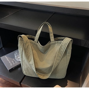 Detail of green checkered canvas tote bag with wide strap on a modern display