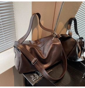 Detail of dark brown Boston tote bag showing smooth PU leather texture and adjustable strap
