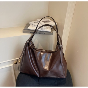 Detail of large brown oil wax leather tote bag with silver buckle and vertical stitching