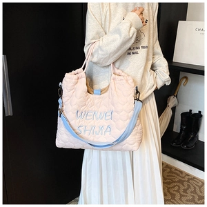 Close-up of pink quilted tote bag with blue letter embroidery and drawstring closure