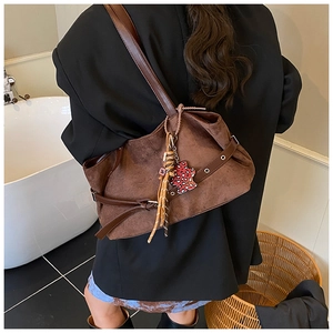 Detail of vintage brown suede shoulder bag with tassel and leopard heart bear charm