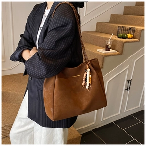 Detail of vintage large brown tote bag featuring braided handle and fashion text print
