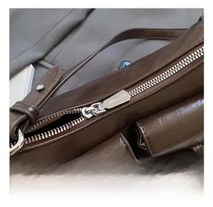 Detailed close-up of premium silver metal zipper and hardware on dark brown leather bag