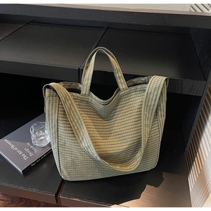 Detail of green checkered canvas tote bag with thick handles and adjustable wide strap