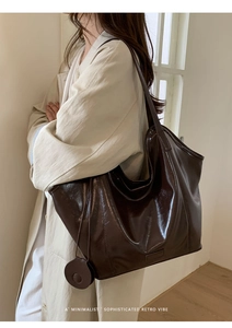 Detail view of deep brown retro leather tote bag with long strap and round charm pendant