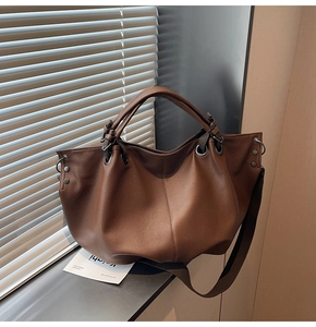 Gros plan d'un sac cabas marron foncé avec texture litchi et rivets en métal