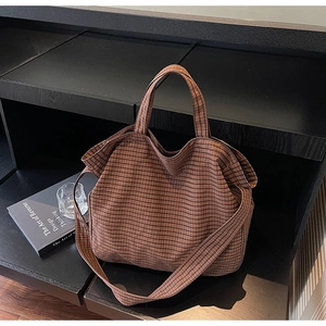 Detail view of large canvas tote bag with brown checkered pattern and wide shoulder strap