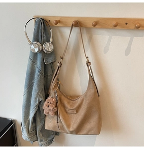 Close-up of khaki suede hobo bag featuring adjustable strap and cute dog plush charm