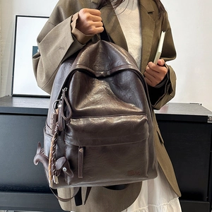 Close-up of a vintage brown leather backpack with horse charm and logo on detail