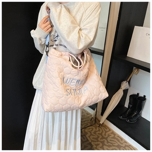 Detail view of pink quilted tote bag with blue embroidery and drawstring closure