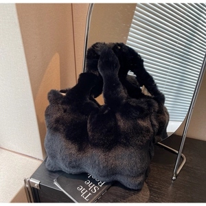 Détail macro du cabas en fausse fourrure noire avec un design plissé et une anse large