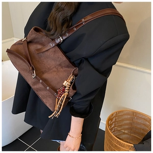 Detail of vintage brown suede tote bag featuring silver metal eyelets and leopard heart charm