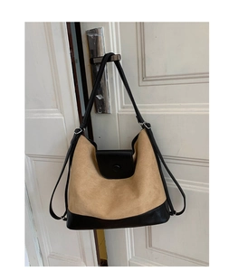 Detail view of contrast stitching handbag with beige suede and black leather accents